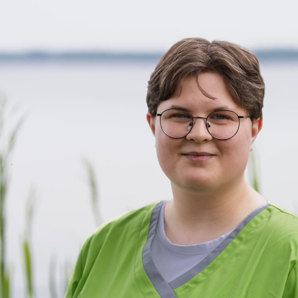Mitarbeiter der Praxis am Glockenturm vor Wasser mit grüner Kleidung.