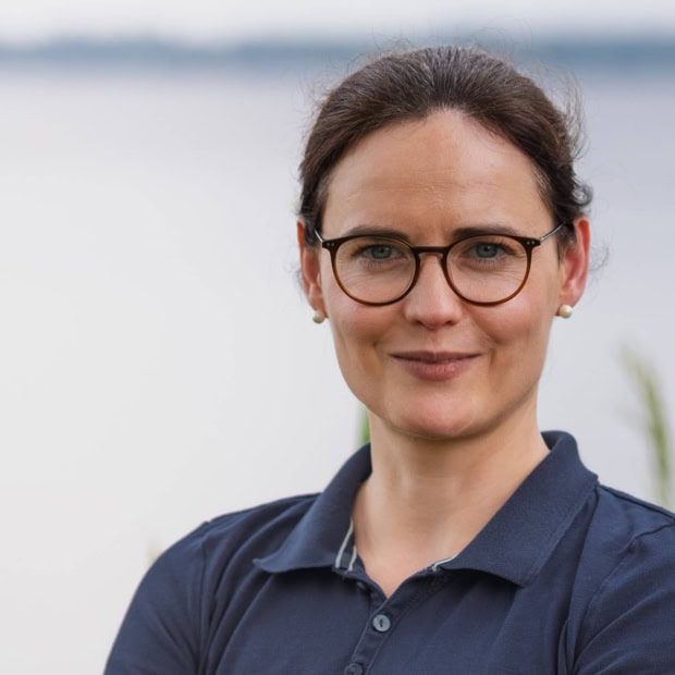 03. Maria-Elisabeth Rohlfing Ärztin mit Brille vor Wasser im Hintergrund bei Praxis am Glockenturm.