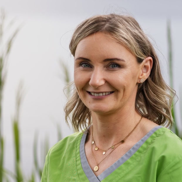 11. Sara Hüggelmeyer Praxis am Glockenturm: Freundliche Ärztin in grüner Praxisuniform.